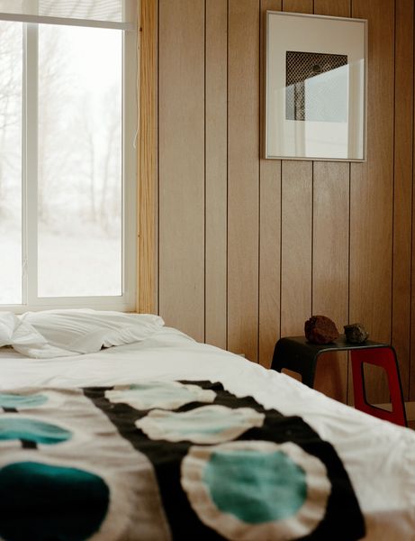 Surrounded by windows on three sides, a bedroom with wood-paneled walls retains vestiges of its sixties past and remains a work in progress. While debating the long-term layout of his now abode, Rael has made homey additions to his quarters, like a painted canvas in adobe by his partner, the artist Joanna Keane Lopez, found rocks, and one of three prints from Icy & Sot, the multidisciplinary art practice of Iranian-born, Brooklyn-based brothers Saman and Sasan Oskouei.