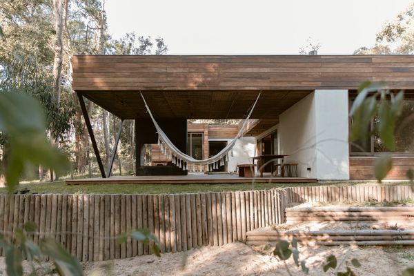 A side view of Facundo Ochoa’s 1,900-square-foot house, situated on a forested lot near a surfable beach in eastern Uruguay. To create a solid foundation, Ochoa laid ballast over the sandy soil. During construction, he got the idea to cut dozens of eucalyptus trunks to delineate part of the sloping perimeter.