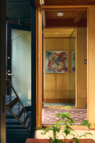 The three-story structure has a pair of external staircases set between the floor-to-ceiling windows and the shutters. A Chinese lacquer chest sits at the center of the ground-floor tatami room, which is used as a tearoom, a yoga space, and a guest room. Untitled 20-10, by Julia Ritson, an Australian artist from George’s hometown, hangs in the entryway. 