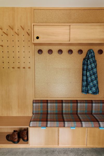 Design-build firm Spot Lab kitted out the entry with built-in cabinetry, seating, and pegboard hangers.