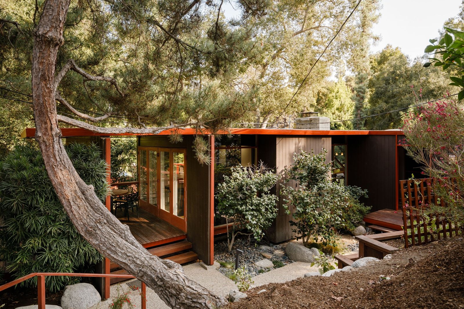 Designed by Buff, Straub, & Hensman, this landmark 1954 home has a massive concrete fireplace, an interior Japanese garden, and a bridge leading down to a series of ponds.