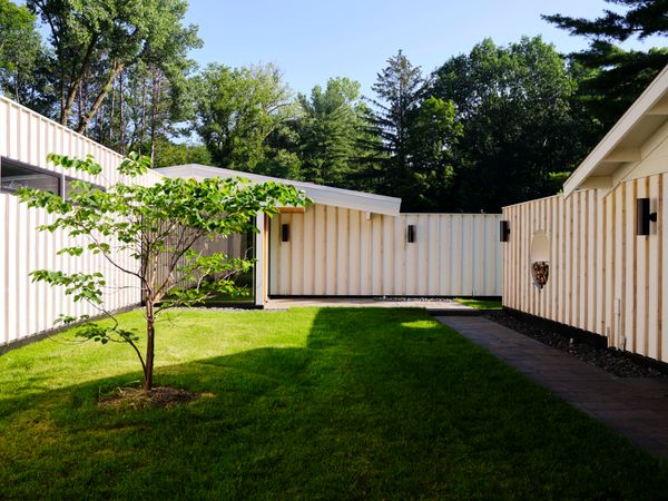 A white dogwood tree grows in the courtyard created by the addition of the ADU on one side and the extended garage wall on the other.