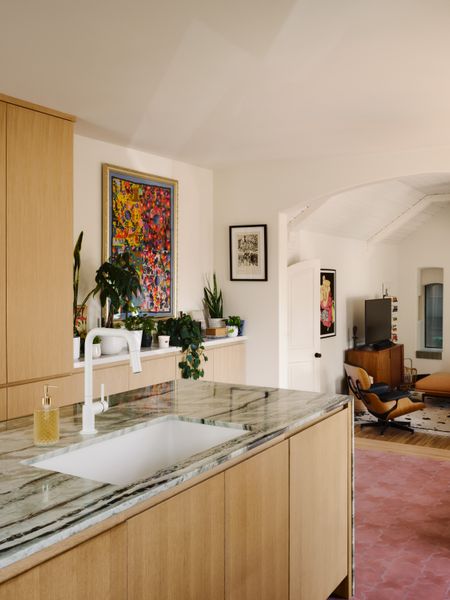 The open kitchen and dining area are on the highest level of the house. At the center is an island sheathed in emerald cloud quartzite. 