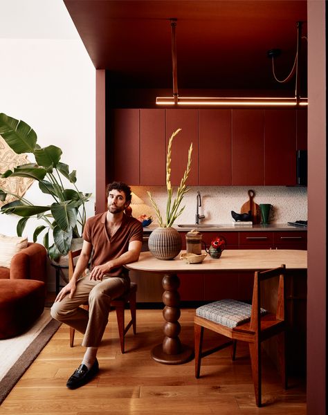 Adam Levy sits in the kitchen of his rented midtown apartment. Rodriguez furnished the apartment with a mixture of vintage pieces, like Adam’s dining chairs, with newer pieces, like the plant stand from West Elm.