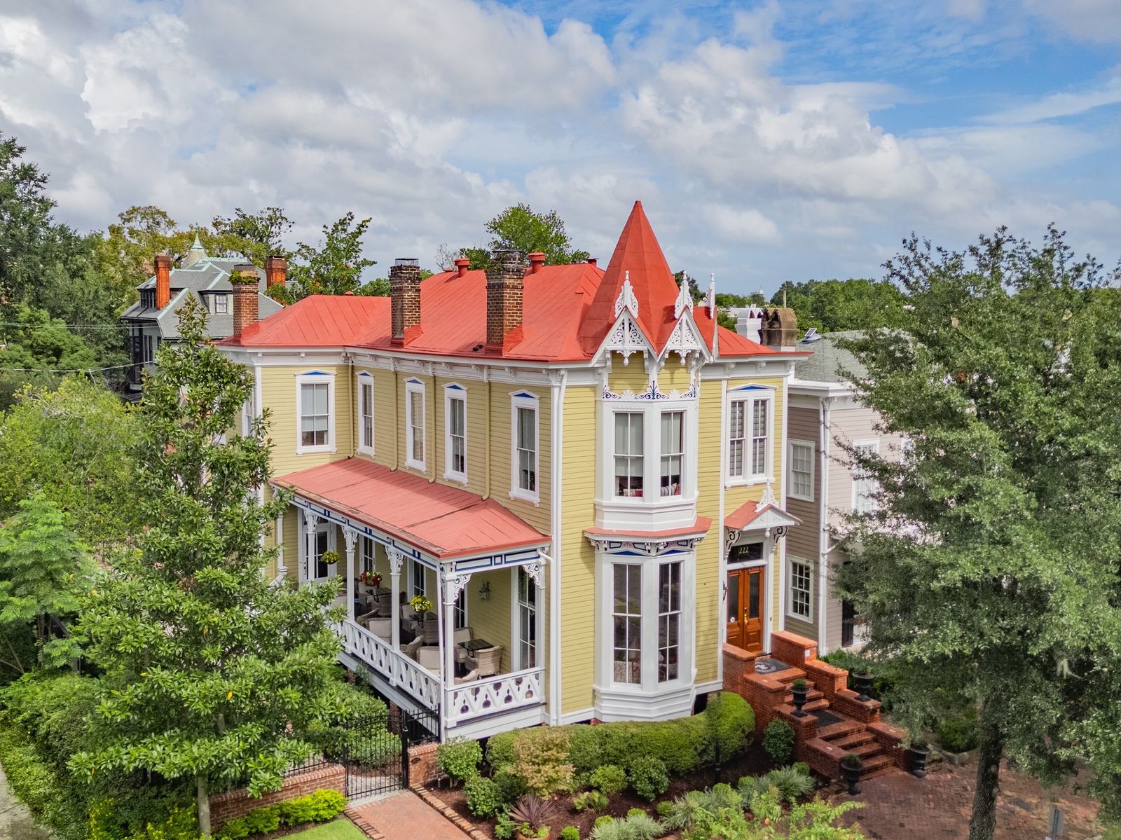 This colorful Savannah home is topped with a turret, and it comes with a large side porch, multiple fireplaces, and a carriage house.