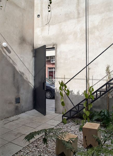 The new residence has a courtyard at the entry, where an iron stair leads to a terrace.