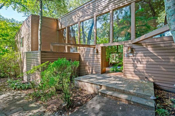 This woodsy ’70s residence has a massive sunroom, a backyard pool, and lots of indoor vegetation.