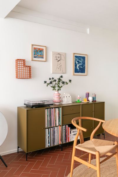 A sideboard in olive green from Montana Furniture stands against the wall in the dining area, which includes Hans Wegner’s Wishbone Chair for Carl Hansen &amp; Søn. Artwork on the wall, from left to right, by: Akiko Mori, Fredrik Karell, Linda Linko, Anna Niskanen.