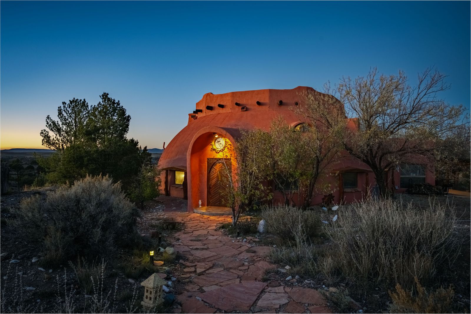 THis curvaceous New Mexico home has an adobe facade, a tree-shaped fireplace, and a ceiling painted to look like the sky.