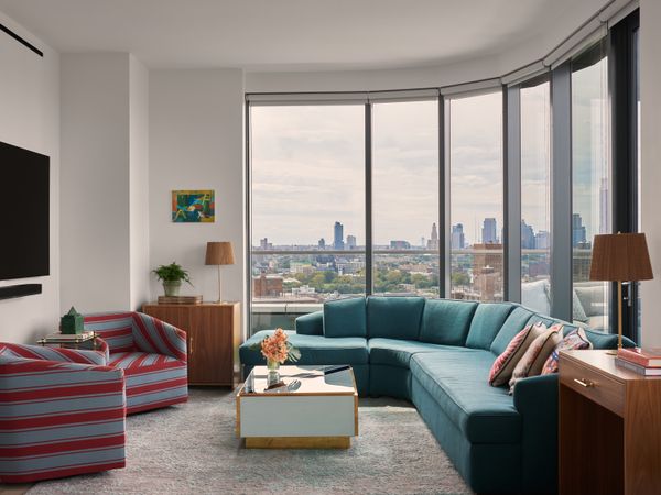 In the living room, McCauley placed a large teal wraparound sofa upholstered in a Pierre Frey fabric that follows the curve of the windows, along with a coffee table by Cosulich