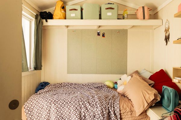 Algere’s cabin is outfitted with a sage-green bulletin board that complements new curtains and storage bins and bedding that fits with the color palette.
