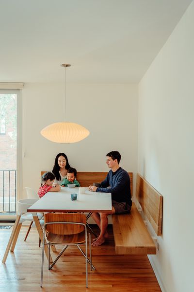 The dining area includes cantilevered oak benches. The Nelson Saucer Bubble pendant, Nelson X-Leg table for Herman Miller, and Eames Molded Plastic side chair are from Design Within Reach.