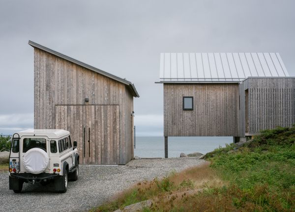 A workshop with a lofted area is contained in its own volume off the driveway. The primary suite rests on stilts at one end, which keeps it at the same level as the living spaces and creates a sight line through to the water.
