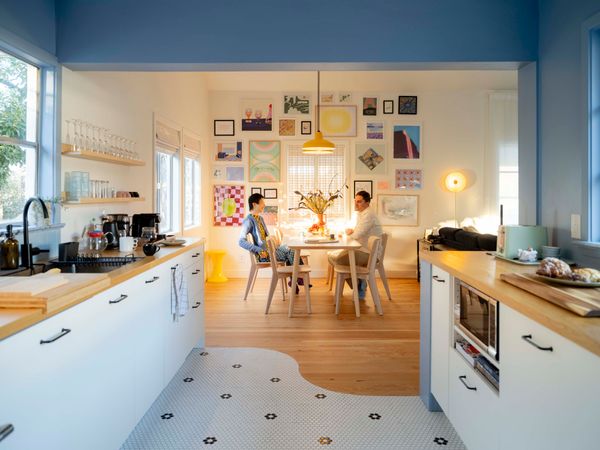 The couple updated the galley kitchen with new Ikea appliances and cabinetry and used a signature curved line to separate the wood floor from black-and-white Merola tile. They used paint from HGTV Home by Sherwin-Williams for the interior walls—Notable Hue in the kitchen and White Flour in the dining room. The Lisabo dining table and chairs, as well as the Varmblixt wall-mounted light, are from Ikea. The Roman window shades with valance are from Arlo Blinds, the yellow Tam-Tam Stool in the corner is by Henry Massonnet, and the pendant lamps are from Hampton Bay.