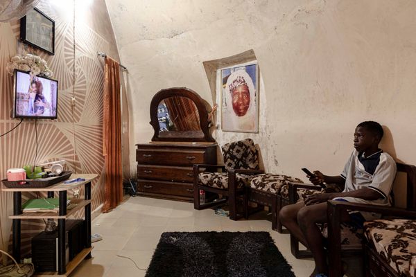 A boy watches TV inside the bubble house where he lives with his family in Ouakam. His bubble house is one of the few that retain a near-original interior layout.