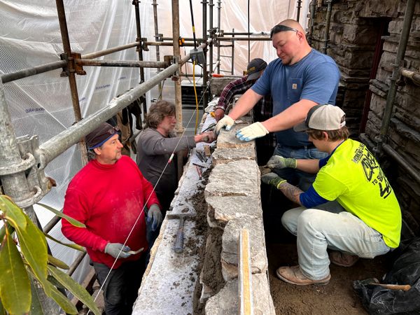 Much of the home’s water damage is due to a lack of flashing where the walls meet roofs and terraces; some say Frank Lloyd Wright omitted it for aesthetic reasons. Here, stone masons place new stones atop newly installed flashing.