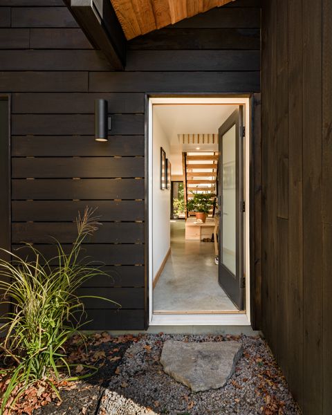 The facade is composed of solid pine boards coated in pine tar, a finish commonly used on houses and boats in Scandinavia. It is durable (it’s supposed to last 100 years, Chelsea says) and protects against rot and insects. Chelsea used Earth + Flax’s Authentic Black pine tar mixed 50/50 with Viking purified raw linseed oil. The sconce is the Breshawna model from Wade Logan.