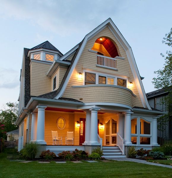 A gracious covered porch and intricate trim details define this custom shingle-style home. Frieze boards, moldings, and window trim—including the surround for an oval picture window at the front entry—are all rendered in AZEK product.