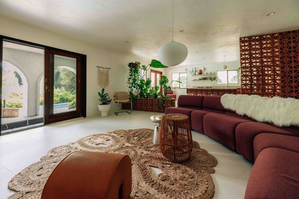 The main living area opens directly to the terrace and pool, with arched views visible through the sliding glass doors. A breeze-block divider separates it from the kitchen.
