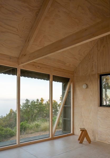 The interior of the cabin, with its 19-foot-tall pitched ceiling, is covered in plywood panels that were glued to the structure’s wood frame—no nails or screws—to achieve a clean, seamless look.
