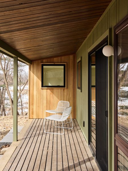 The raised, covered porch is reminiscent of a Japanese <i>engawa</i>, a veranda-like transitional space that connects the home to the landscape. The renovation expanded views to the lake with new windows in the primary bedroom and bath, and sliders that replaced a standard solid door in the living area.