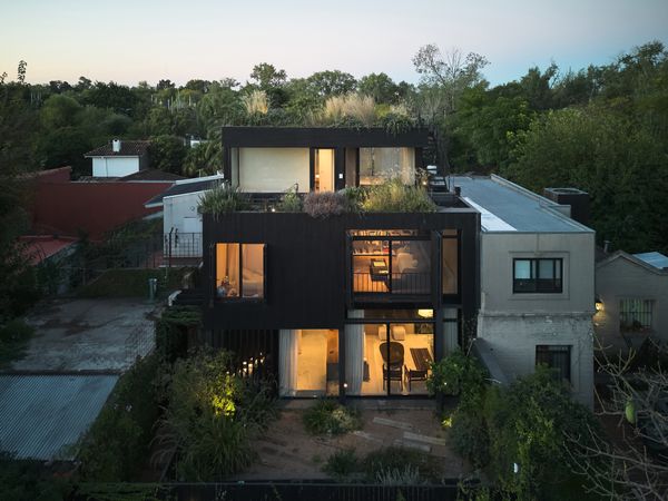 The exterior of the house is clad in charred kiri wood, inspired by the Japanese <i>yakisugi</i> technique. On the second level are three bedrooms and a family room with a small balcony.