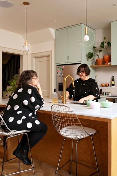 The kitchen cabinets are covered in a softer green, Teresa’s Garden by Farrow & Ball. The couple used Wimborne White for the rest of the kitchen. The Frost mosaic backsplash is from Fireclay Tile, and the countertops are from Mondial Tiles. The Eames wire stools are from Design Within Reach. The appliances are from Thermador and Fisher & Paykel. The Axor Starck faucet is from Ferguson Home. The Aura pendant lights are from Ladies & Gentlemen Studio.
