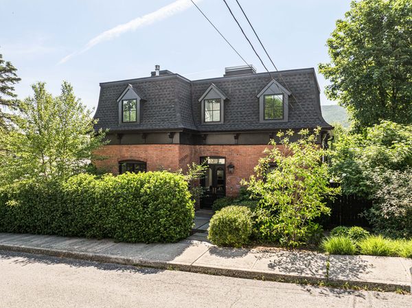 From Davis Street, the house presents as a composed two-story façade; from Ackerman Street, its full three-story scale and tower come into view.