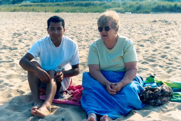 Luis and my grandmother sitting on a beach while my sister and I were most likely boogie boarding.