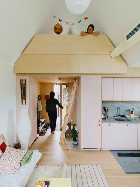 The kitchen features pale pink Reform cabinets and a blue-green quartzite backsplash. Lenore, a textile print designer, peeks out from a small loft she turned into an art studio.