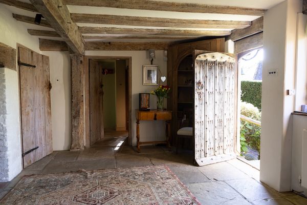 Behind the oak front door, the entrance hall was opened up to reveal original Tudor windows, fireplaces, and exposed timbers, with a gallery above. Concealed skylights bring additional natural light into the space.