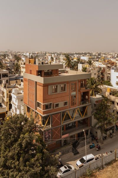 Newly built on the razed site of Sridhar Krishna’s childhood home in Bangalore, India, the house’s structure was designed by Uppar Basawaraj of EarthSpace Architects. The interiors of the 3,300-square-foot, three-level space were completed by designer and architect Sriviji Nachimuthu of Studio D’ Nachi. The building stands out with its distinctive facade of terra-cotta bricks arranged in various patterns alongside surfaces covered in gray oxide plaster and a series of yellow-painted galvanized iron struts.
