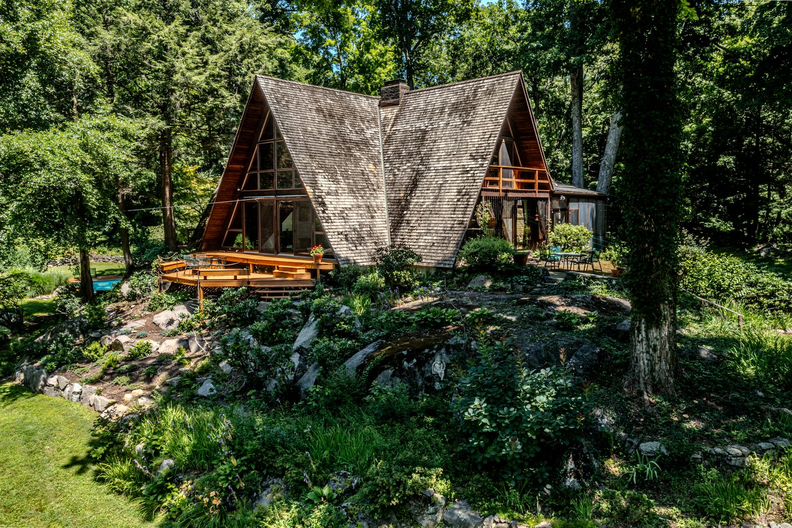 Built in 1966, the quirky Westchester home has striking triangular rooflines and a series of decks made for gazing out over sculpture-dotted gardens and serene woodland.

