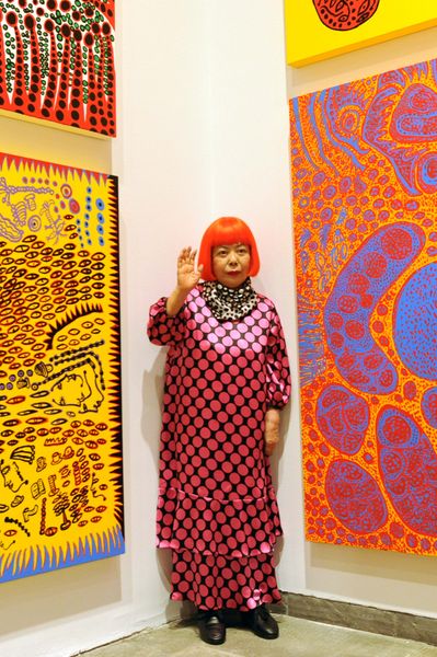 Japanese artist Yayoi Kusama, who died in August at the age of 97, poses in front of her distinctive art.