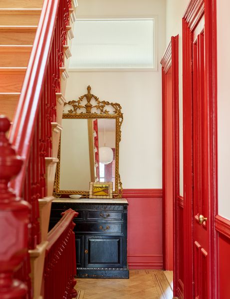 The home has a bold red entry, muted pinks on the upper level, and rusty tones elsewhere. 