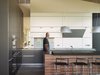 Modern home with Kitchen, Wood Cabinet, White Cabinet, Pendant Lighting, Concrete Floor, Cooktops, and Wall Oven. The minimal kitchen design is apportioned with tri-colored cabinets and a clever opening through that overlooks the gallery. Photo 8 of Wyoming Residence