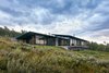 Modern home with Exterior, House Building Type, Concrete Siding Material, Green Roof Material, Metal Siding Material, and Shed RoofLine. From the entrance, the cantilevered structure wraps around to reveal a comparatively more modest side that bows to the mountains and floats on the meadow. Photo 15 of Wyoming Residence