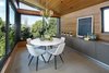 An informal dining area sits just off the kitchen. Floor-to-ceiling windows on the second-story paired with wood-paneled walls make the room feel like it is up in the trees. Photo 7 of Cohen Residence modern home