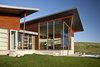 The ATA design team wanted to bring that indoor-outdoor California feeling to this home in Wyoming by highlighting its physical connection to the land. Because of the climate, however, they opted for expansive windows, not expansive openings, to capture the beautiful quality of light and the picturesque view. These windows are layered with concrete, steel and wood to converge in textural detail, accenting the sloping wings and defining a natural focal point. Photo 4 of Casper Residence modern home