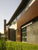 The first floor base is mostly solid, in response to the harsh Canadian winter, and is clad in layer of stone and wood. It reads heavy and rooted to the earth. As the façade lifts up and away from the grade, it is wrapped in wood and detailed as a rain-screen, which stands proudly on the stone below it. Photo 2 of Davis Residence modern home