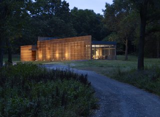 The Coffou Cottage sits in an L-shaped at the end of a private road.  This image shows how red cedar is utilized to create thin slats along the facade, as well as horizontal and vertical board-and-batten siding.