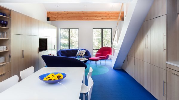 Simon preserved the structural beams from the building, but put a fresh sprin on the rest of the surfaces. The Plume sofas by Ligne Roset are upholstered in a bright cobalt blue quilted blend fabric, while the Womb Chair—designed by Eero Saarinen for Knoll—is finished in a bold magenta fabric.