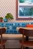 Modern home with Dining Room, Bench, Chair, and Table. The aloha spirit runs deep in Mahina & Sun’s, where the walls are covered with a shaka wallpaper by Andrew Mau. The cushions on the banquette seats were made with archived prints by Tori Richard, which were also used to create the headboards in the guest rooms and the men’s uniforms. Photo 7 of The Surfjack Hotel & Swim Club