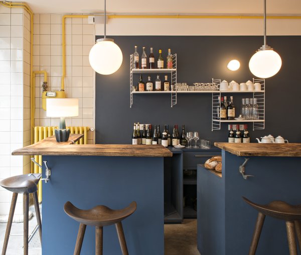 A set of wall-mounted String shelves, an iconic 1949 design by Nisse Strinning, provides storage for the casual bar, which features stools from By Lassen and wooden countertops.