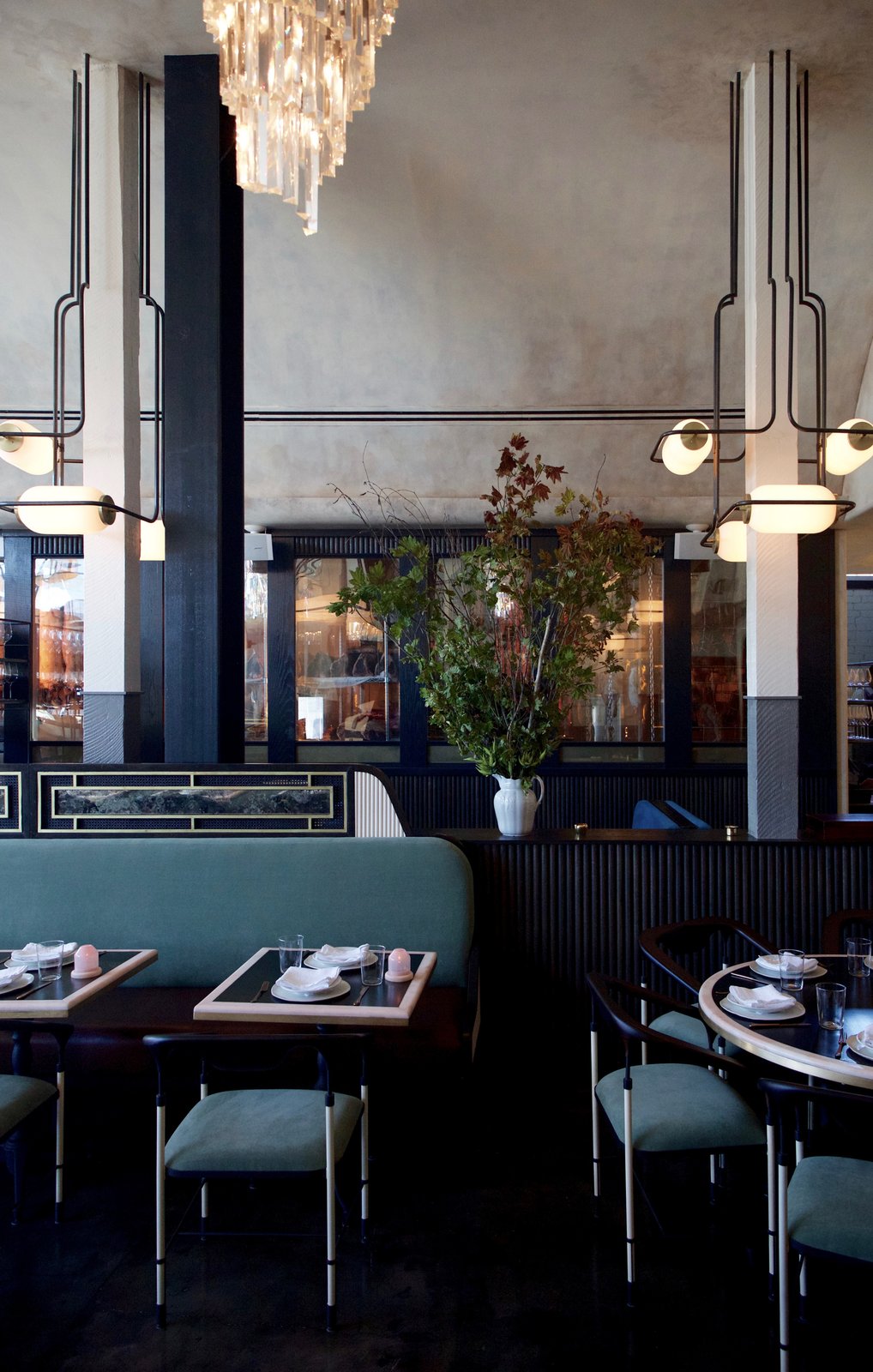 Steel-and-wood chairs produced by Nicaragua-based Maderas Collective, paired with light green upholstered cushions made locally in New York, furnish the main dining hall.