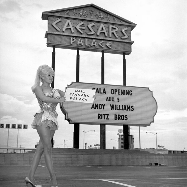 A Caesars Palace employee poses by the marquee prior to the hotel's grand opening.