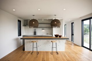 The kitchen island is made of concrete with an oak top and black steel edging—an industrial element within a project that celebrates nature.