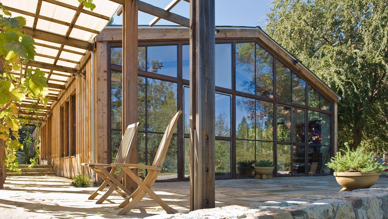 The gut renovation by Lundberg Design features cathedral ceilings, a completely glazed-end façade, and a dropped floor level in the living area. Additional elements include a Finnish soapstone stove in the center for heat; steel trusses and windows to add some visual detail; and a trellis on the front to add depth and texture to the façade.