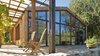 Modern home with Outdoor, Large Patio, Porch, Deck, Stone Patio, Porch, Deck, and Trees. The gut renovation by Lundberg Design features cathedral ceilings, a completely glazed-end façade, and a dropped floor level in the living area. Additional elements include a Finnish soapstone stove in the center for heat; steel trusses and windows to add some visual detail; and a trellis on the front to add depth and texture to the façade. Photo of McDonald Residence