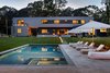 Modern home with Exterior, House, Wood Siding Material, and Prefab Building Type. rear facade and yard, view from poolhouse Photo of Springs Residence